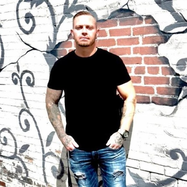 Adam Harper standing in front of a painted brick wall