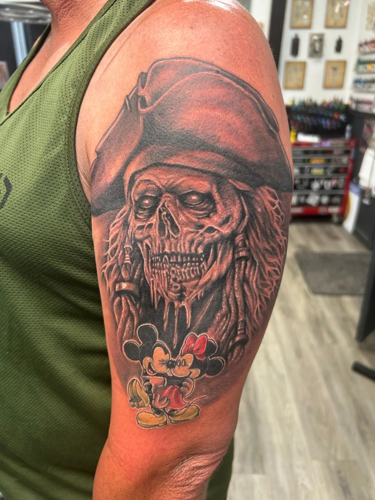 Black and grey skeleton pirate with a small color Mickey and Minnie Mouse tattooed on an upper arm by Adam Harper
