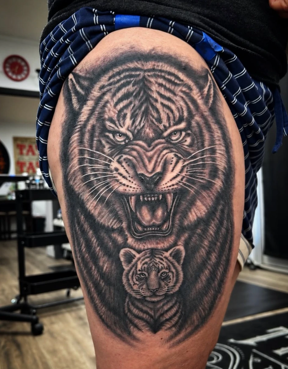Black and grey realistic tiger and cub tattoo on a thigh by Adam Harper