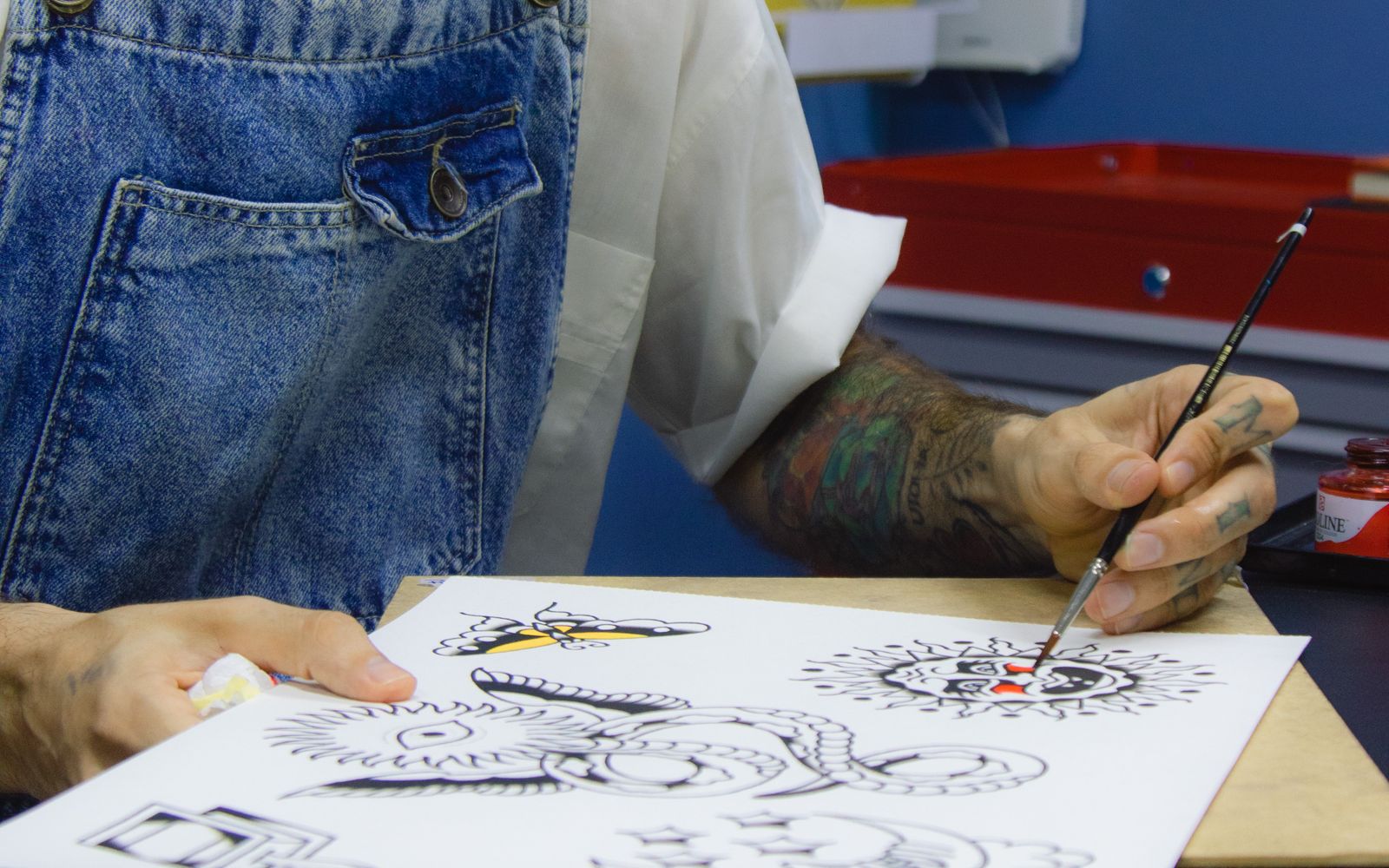 Tattoo artist sketching a custom design by hand at a shop desk