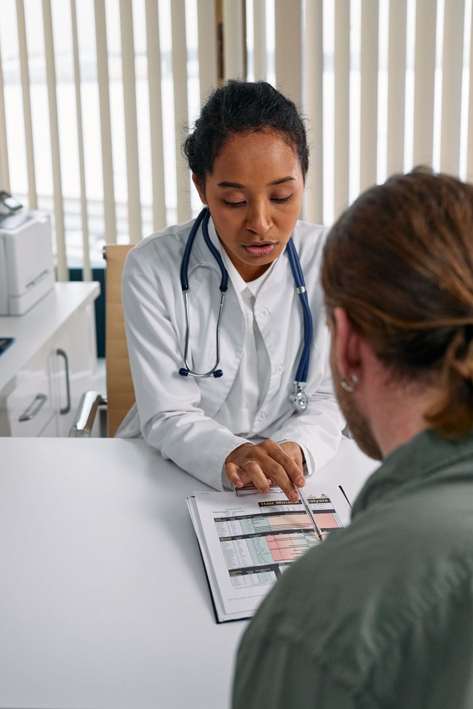 Doctor in a white coat going over a chart with a patient at a desk