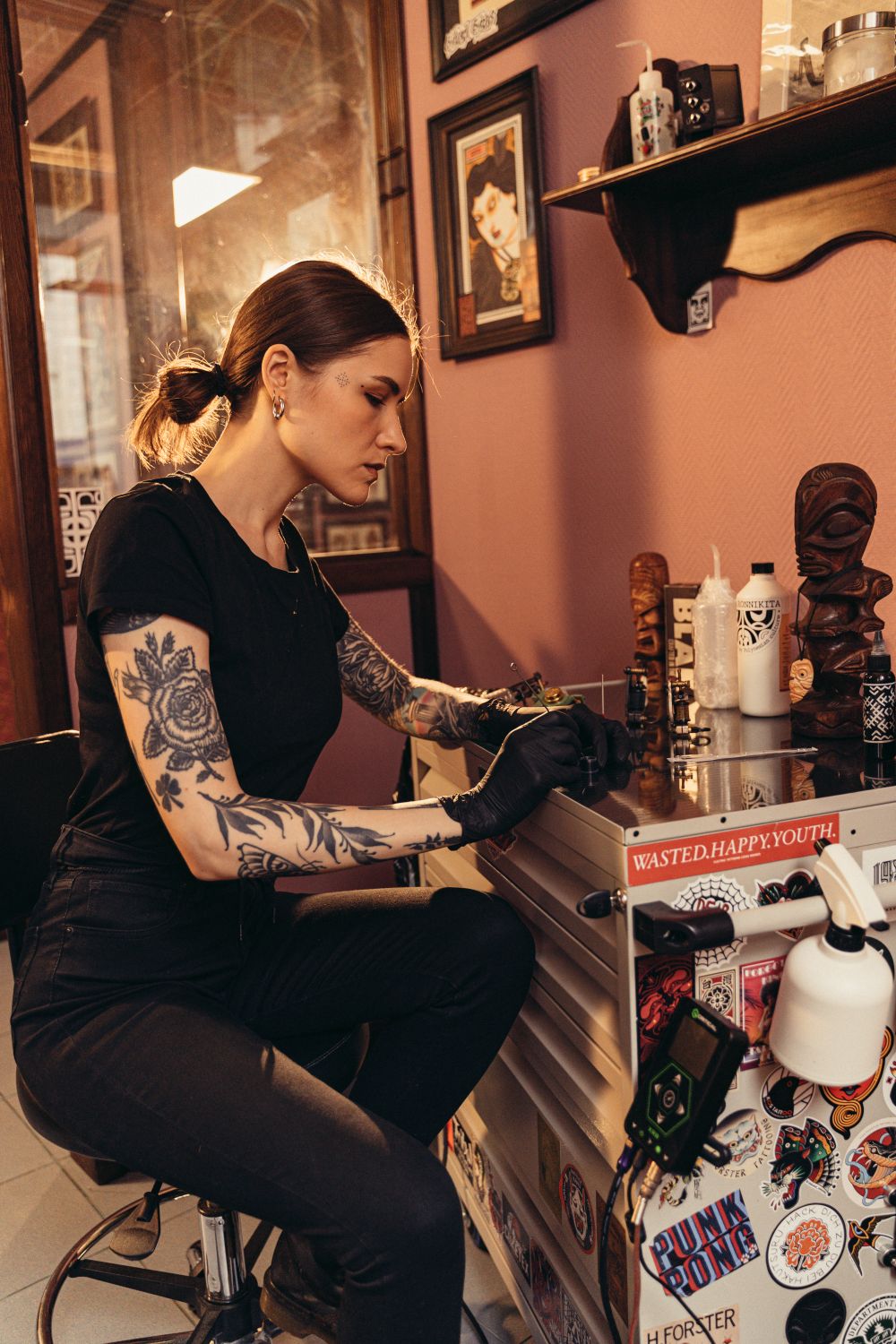 A tattoo artist working in a warmly decorated studio surrounded by art