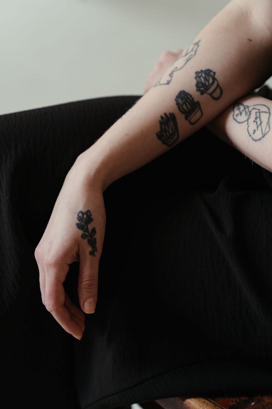 Forearm and hand with several small separate tattoos, including potted plants and line doodles