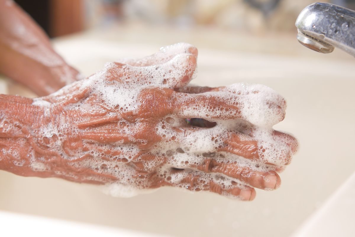 Soapy hands lathering together under a running tap