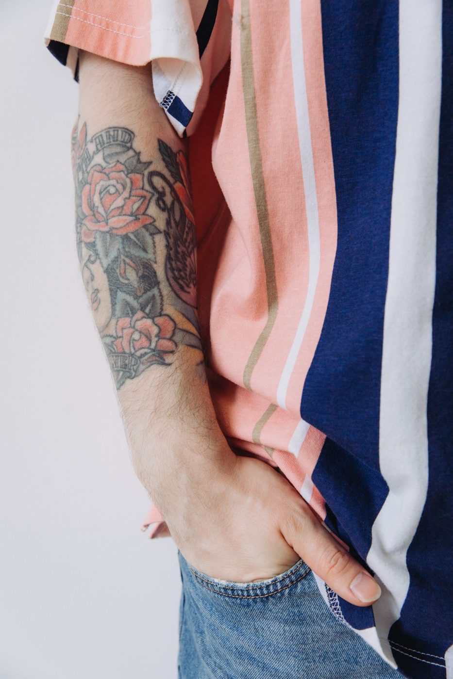 Forearm tattooed with red roses and bold black outlines in a traditional style