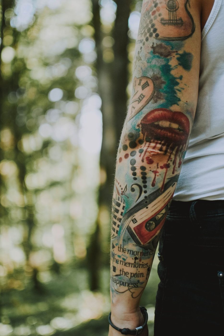 Forearm sleeve of colorful illustrative tattoos with teal and red paint-splash effects